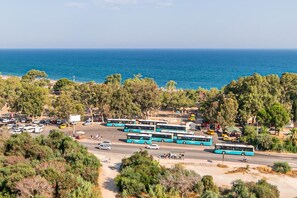 A coastal area with multiple buses parked, a road with vehicles, and a view of the sea. - Lara Park Suites (Antalya)