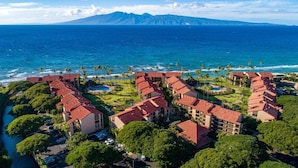 Een resort met meerdere gebouwen, een zwembad en uitzicht op de oceaan en bergen.