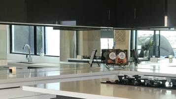 A modern kitchen with a large island, stainless steel appliances, and pendant lighting.
