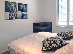 Ein Schlafzimmer mit einem Bett, einem Fernseher und einem Fenster.