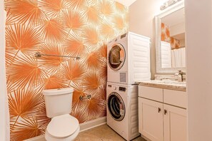 Ein kleines Badezimmer mit Toilette, Waschmaschine und Waschbecken.