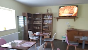 Un coin repas avec une table en bois, des chaises et un téléviseur fixé au mur.