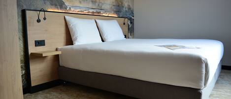 Um quarto moderno com uma cama grande, cabeceira com alto-falantes embutidos e parede texturizada atrás da cama.