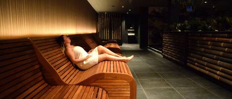 Zona de spa con bancos de madera y suelo de baldosas.