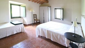 Un dormitorio con cama, una silla, una mesa y un ventanal.