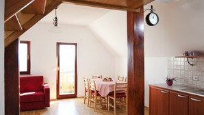 Una cocina amplia con vigas de madera, un comedor con sofá rojo y vistas por un ventanal.