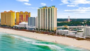 Un hotel costero con varios edificios altos, una playa y un parque de atracciones a lo lejos.