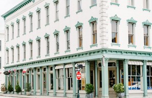 A historic building with a white facade and green trim. It features a row of large windows with green shutters, a covered entrance with columns, and a 'Do Not Enter' sign. - Chic and Bright in Downtown Savannah by Lucky Savannah (Savannah)