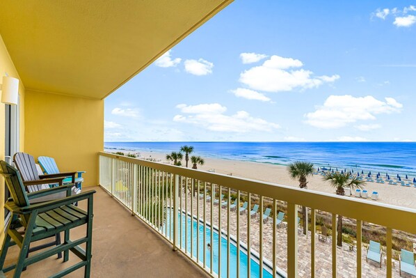 A balcony with a view of the beach and a pool.