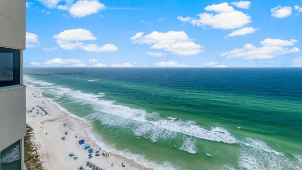 A beach view from a high-rise building with a pier in the distance.