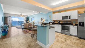 A modern kitchen with a central island, stainless steel appliances, and a view to the outside.