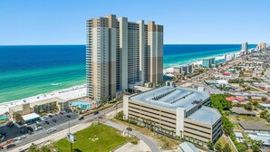 A high-rise hotel with multiple floors, a parking garage, and a beach view.