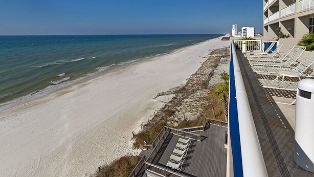 A beach view from a balcony with sun loungers and a railing. - BEAUTIFUL BEACHFRONT! 1 MILE W OF PIER PARK! (Panama City Beach)