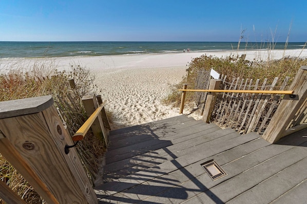 Eine Holztreppe führt zu einem Sandstrand mit freiem Blick auf das Meer.