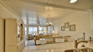 A spacious kitchen with a marble countertop, a stainless steel sink, and a dining area with a table and chairs.