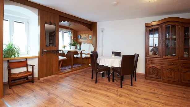 A dining area with wooden flooring, a white table, and chairs. There is a wooden cabinet with glass doors and a mirror on the wall. - Spacious apartment in the old town, 90 sqm, 1st sep. Bedroom (Wasserburg am Inn)