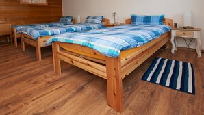 A room with two wooden beds, each with blue and white striped bedding, a wooden nightstand with a lamp, and a wooden floor. - Spacious apartment in the old town, 90 sqm, 1st sep. Bedroom (Wasserburg am Inn)