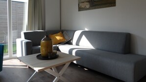 Ein modernes Wohnzimmer mit einem grauen Sofa, einem kleinen Tisch und einem Bild an der Wand.