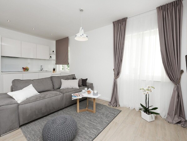 A modern living room with a grey sofa, a coffee table, and a potted plant. - Villa in Nin With Stunning Sea Views (Nin)