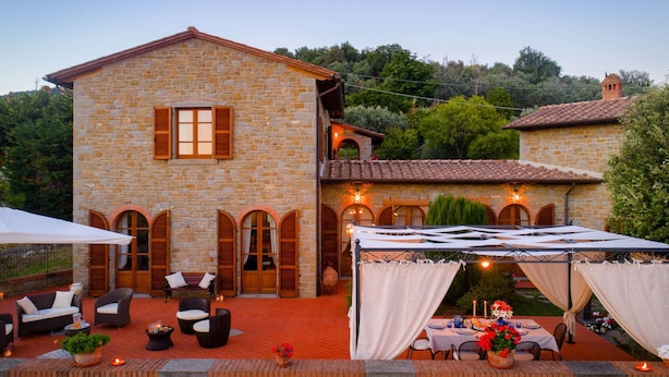 A stone building with a balcony, outdoor seating, and a dining area with a tent. - Luxurious Villa in Cortona Tuscany with Hot Tub (Cortona)