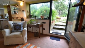 Un salón acogedor con un sofá blanco, un tapete a rayas y vistas a un jardín exuberante a través de un amplio ventanal corredera.