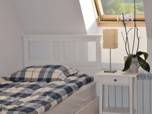 Une chambre à coucher avec un lit, une table de chevet avec une lampe et une plante en pot.