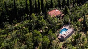 An aerial view of a house surrounded by dense forest, with a swimming pool in the foreground. - Tuscan Castle View Grand Villa (Castiglion Fiorentino)