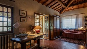 A rustic interior with a wooden ceiling, a dining table with a vase of flowers, a sofa, and a cabinet. - Tuscan Castle View Grand Villa (Castiglion Fiorentino)