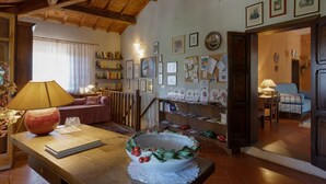 A cozy living room with a wooden table, a sofa, and a dining area with a wooden bench. - Tuscan Castle View Grand Villa (Castiglion Fiorentino)