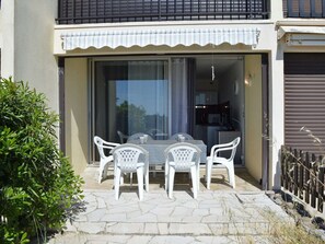 A patio with a table and chairs, a sliding glass door, and a small garden area.
