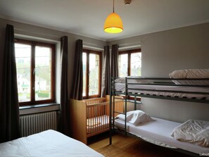 A dormitory room with bunk beds, a crib, and large windows with curtains. - Waimes Wellness & Nature Villa (Waimes)