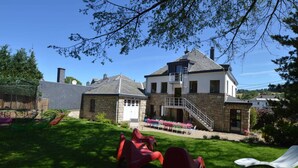 A two-story house with a stone facade, a garage, and a covered patio area with outdoor seating. - Waimes Wellness & Nature Villa (Waimes)