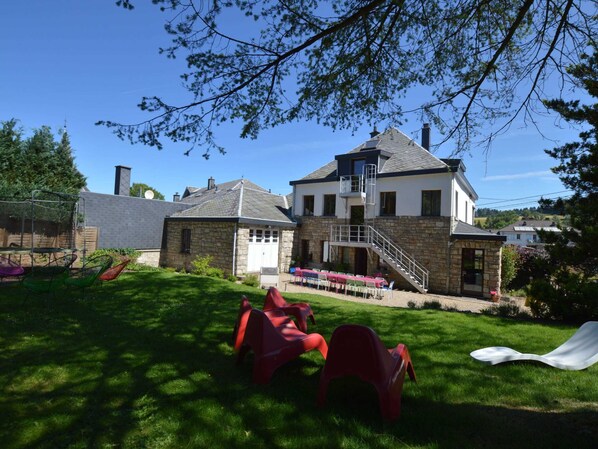 A two-story house with a stone facade, a garage, and a covered patio area with outdoor seating. - Waimes Wellness & Nature Villa (Waimes)