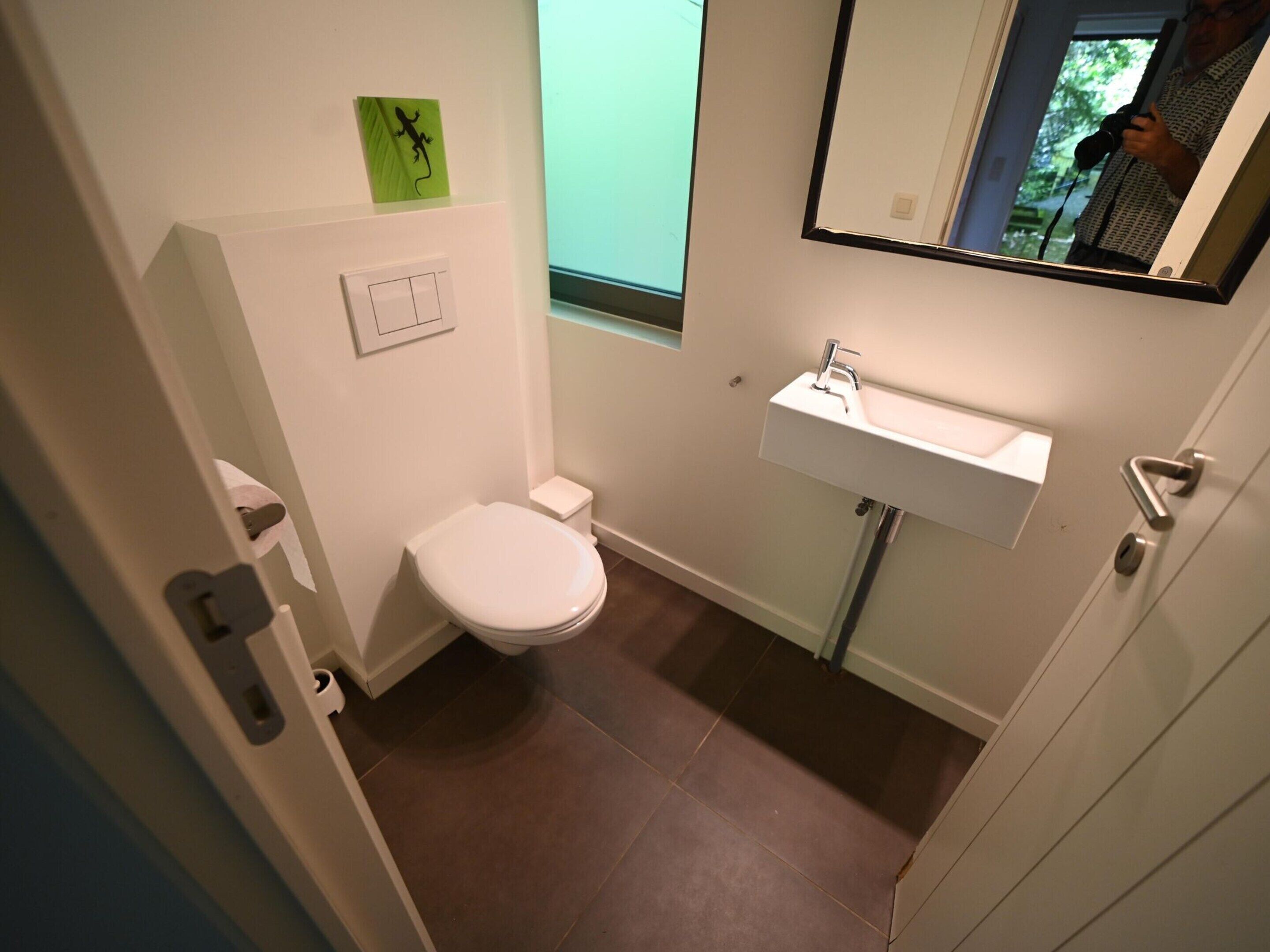 A small, modern bathroom with a toilet, sink, and a mirror.