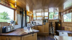 A wooden cabin-style kitchen with a central island, wooden cabinets, a microwave, and a toaster.