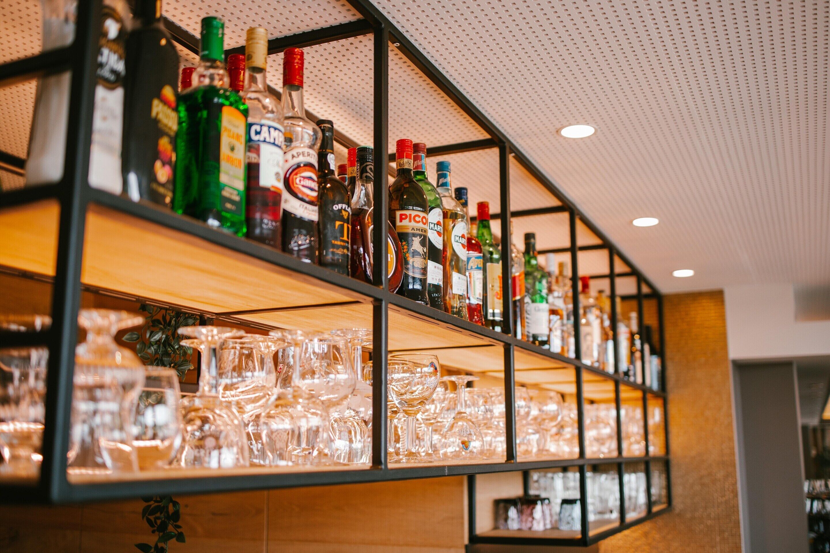 Zona de bar amb prestatges plens de garrafes de licors i gots.