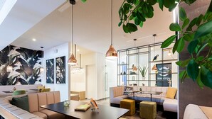 Un intérieur moderne avec un espace salon aux lignes courbes, des luminaires suspendus et une plante visible.