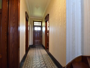 Un pasillo con alfombra estampada, puertas de madera y un techo decorativo.