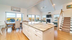 A spacious kitchen with a large island, a dining area with wicker chairs, and a view of the beach. - Custom Single Family home with Expansive Bayfront views! (Wildwood Crest)