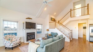 A spacious living room with a fireplace, a sofa, a patterned armchair, and a staircase leading to an upper level. - Custom Single Family home with Expansive Bayfront views! (Wildwood Crest)