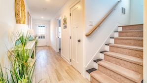 A hallway with a wooden floor, a staircase with carpeted steps, and a door with a sign above it. - Custom Single Family home with Expansive Bayfront views! (Wildwood Crest)