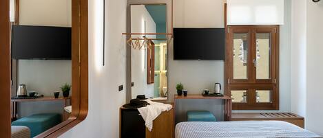 Una habitación de hotel moderna con una cama grande, un escritorio con silla, un pequeño rincón de descanso, un televisor montado en la pared y un espejo amplio.