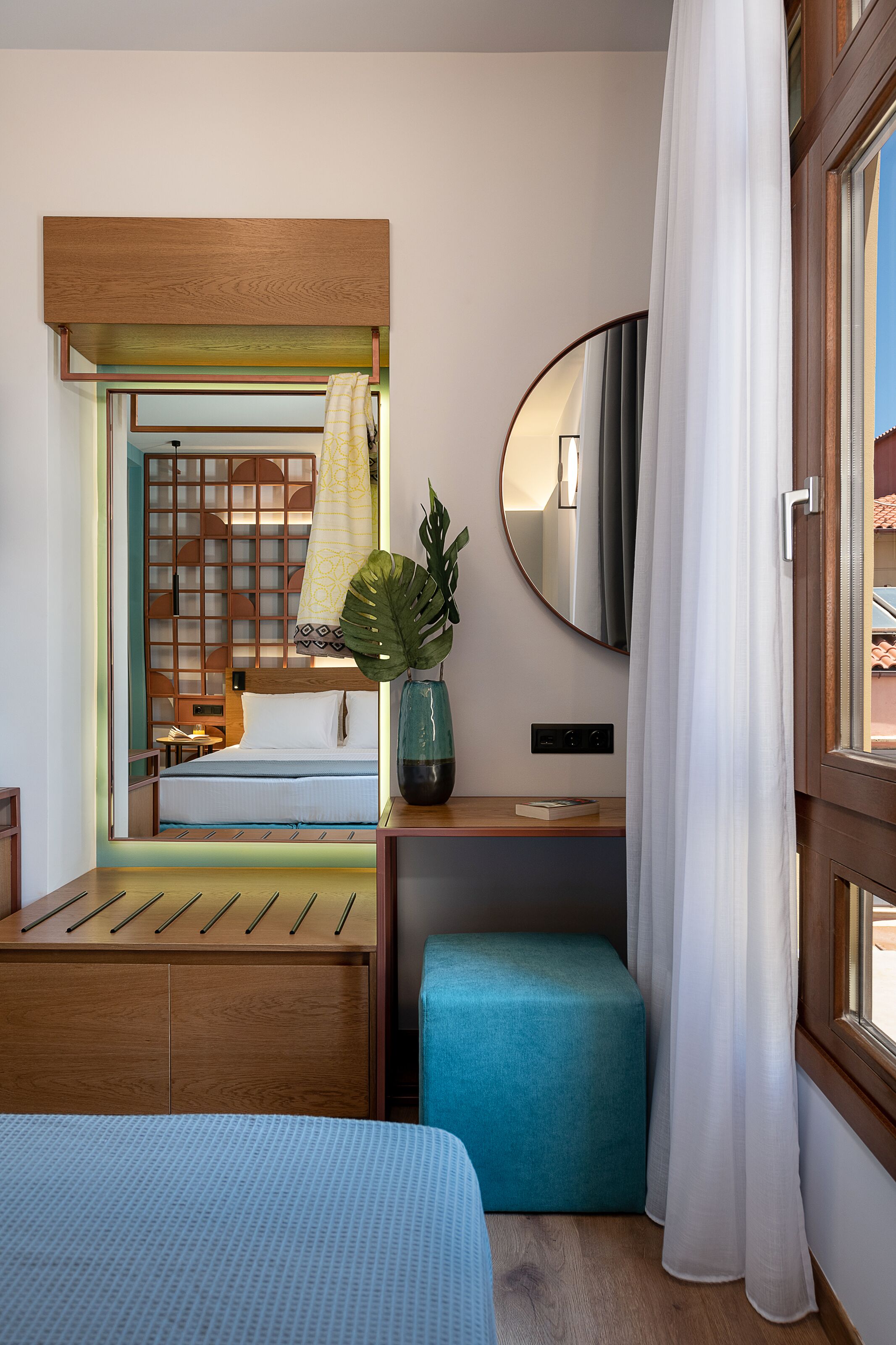 Une chambre d’hôtel comprenant un lit, une table de chevet, un miroir, une fenêtre avec des rideaux et une vue sur l’extérieur.