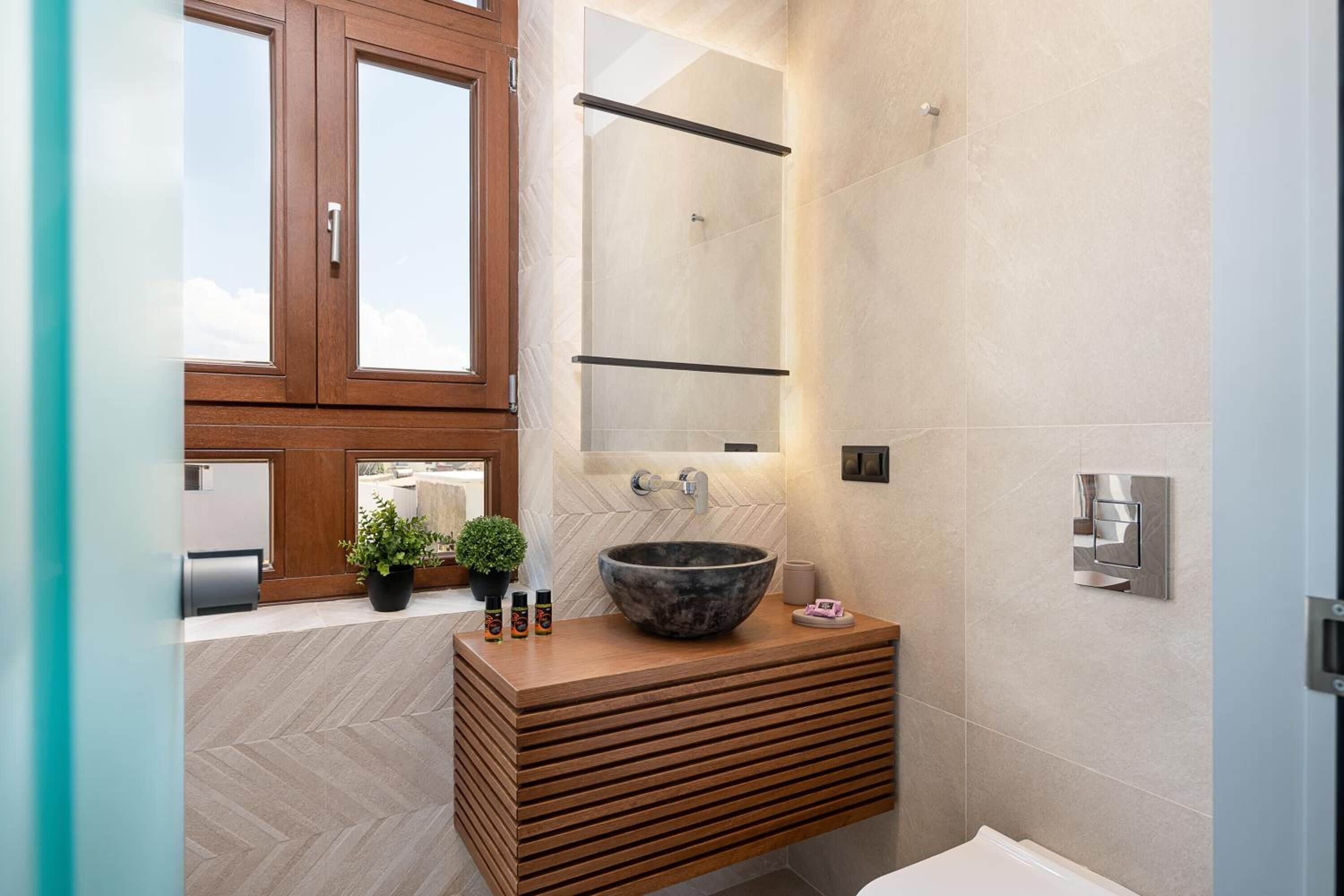 A modern bathroom with a wooden vanity, a large mirror, and a vessel sink.