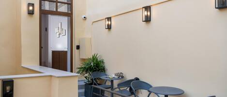 A modern outdoor seating area with a staircase, a potted plant, and a door with a geometric design.