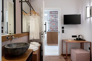Un baño moderno con un espejo grande, un tocador de madera, un lavabo y un perchero para toallas.