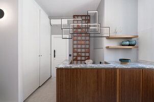 Una cocina moderna con una isla de madera, armarios blancos y objetos decorativos en estantes.