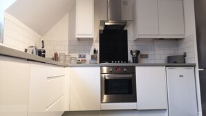 A modern kitchen with white cabinetry, a stainless steel range, an oven, and a built-in dishwasher. - Marina Apartment by Switchback Stays (Penarth)