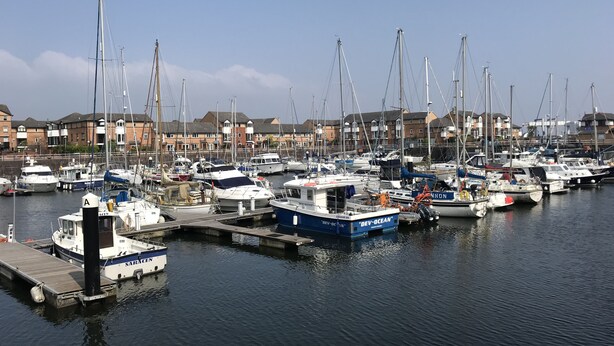 A marina with multiple boats docked, surrounded by residential buildings. - Marina Apartment by Switchback Stays (Penarth)