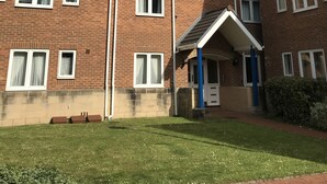 A multi-story brick building with a flat roof, multiple windows, and a small entrance with a blue door. - Marina Apartment by Switchback Stays (Penarth)
